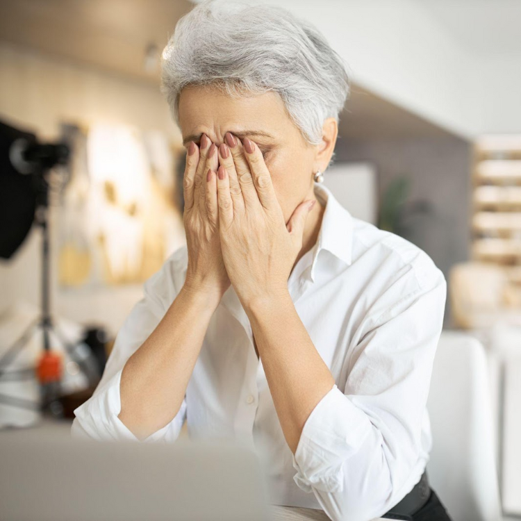 Mulher com as mãos na cara com sintomas de stress