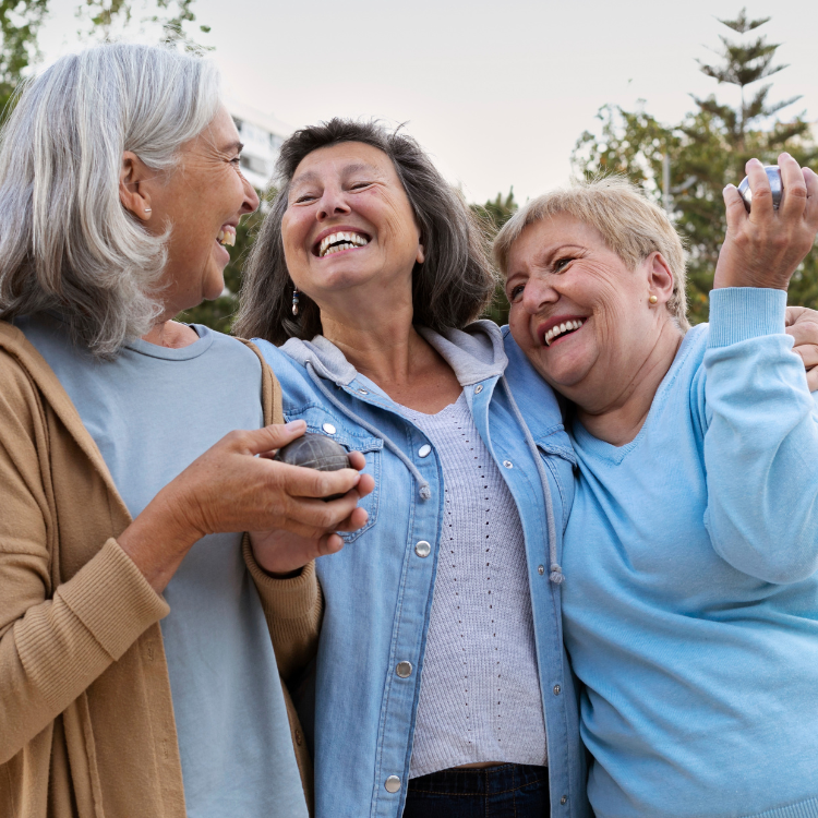 Três senhoras abraçadas a sorrir